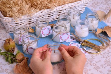 Sonbahar Şükran Günü hediyeler getirir el yapımı sonbahar düğün hediyeleri yapma süreci, kadın eli zanaatkar mumu ve dekorasyon için jüt kurdele, beyaz mavi balkabağı rengi parti dekorasyonu