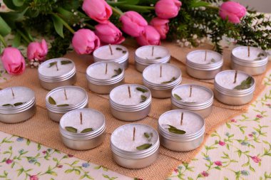 Düğün, mum hediyeleri, jüt pembe laleler arka plan, bahar partisi dekorasyonu el yapımı mumlar teneke kutularda.