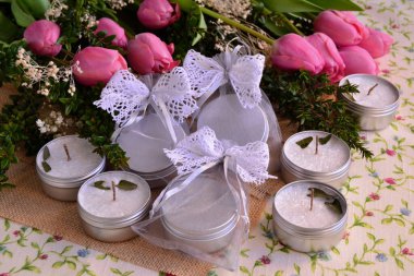 Düğün için mum hediye paketleri beyaz dantel yay, jüt ve pembe laleler arka plan, bahar etkinliği el yapımı hediyeler