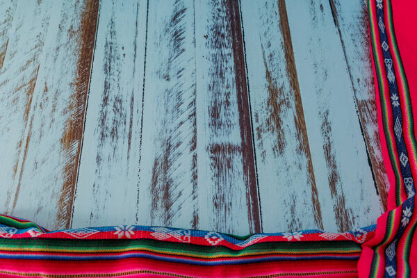 Деревянный стол с тканями, сделанными вручную людьми, которые живут в перуанских горах с доиспанских времен с вышивкой и яркими красками