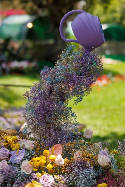 Floral arrangement with a watering can producing flowers as if they were water