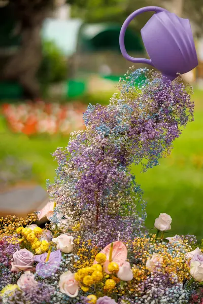 Floral arrangement with a watering can producing flowers as if they were water