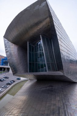 Bilbao, İspanya, 12 Temmuz 2024 - Bilbao 'daki Guggenheim Müzesi gün ışığına çıkıyor, titanyum kaplaması güneş altında parlıyor. Frank Gehry tarafından tasarlanan bu mimari mucize nehir kıyısında sıvı eğriler ve kalın formlar sergiliyor.