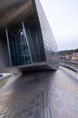 Bilbao, İspanya, 12 Temmuz 2024 - Bilbao 'daki Guggenheim Müzesi açık gün ışığında görkemli bir şekilde nehir kıyısında duruyor, titanyum yüzeyi güneşin altında parlıyor. Frank Gehry 'nin yenilikçi mimarisi tamamen sergilenmektedir.