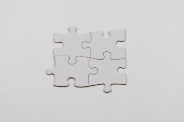 Beyaz yapboz parçaları beyaz arka planda dimdik duruyor, temiz ve kavramsal bir görsel yaratıyor.