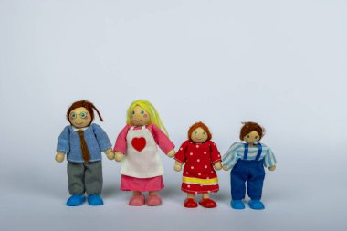 Tahta oyuncak aile beyaz bir arkaplanda el ele tutuşup birlik ve aşkı sembolize ediyor. Birbirine bağlı bir ailenin mükemmel bir temsili