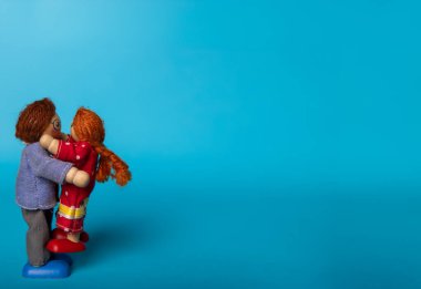 Wooden toys of a father and daughter hugging, set against a blue background. A heartwarming representation of family love and affection clipart