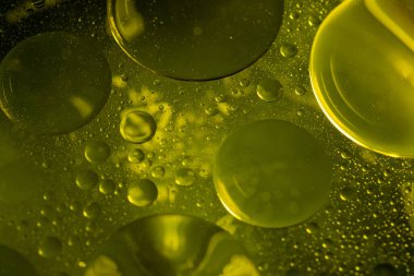 Sarı sıvıda renkli yağ kabarcıklarının makro görüntüsü.