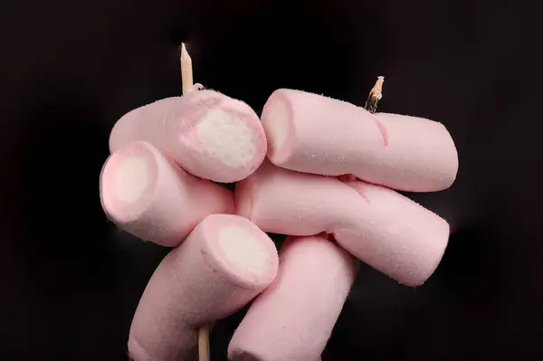 stock image marshmallows placed on wooden skewers, standing out against a black background, drawing attention to their smooth and fluffy texture.