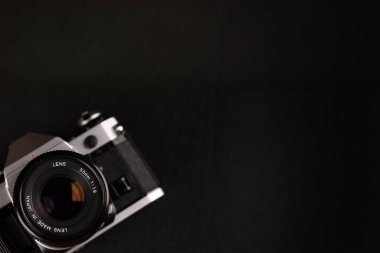 Sol köşede eski fotoğrafçılık ekipmanlarının zarafetini sergileyen büyük siyah bir arka planı olan klasik bir kamera..