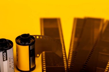 Analog film rulolarının yakın plan çekimleri. Parlak sarı bir yüzeye serili gelişmiş filmler. Eski fotoğraflara bir övgü.
