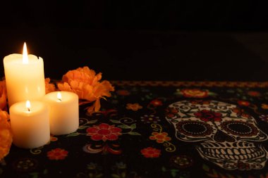 Solda yanan üç mumdan oluşan canlı kadife çiçekleriyle çevrili bir manzara. Sahne, siyah bir arkaplana karşı mum ışığıyla vurgulandı. Ölü bir giysi günü, şenlikli bir havayı çağrıştırıyor..
