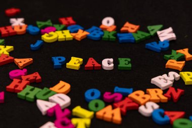 Çok renkli ahşap harfler üzerine merkezi bir odak noktası, siyah bir zemin üzerine kurulmuş 