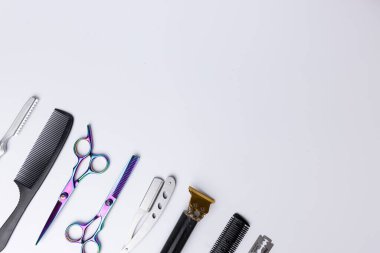 Beyaz arka planda düzenlenmiş açılı berber araçlarının ayrıntılı görünümü. Makas ve ustura içeren aletler, resmin sol tarafına yukarıdan aşağıya doğru düzgünce yerleştirilmiştir.