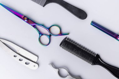 Makas ve makas da dahil olmak üzere, temiz beyaz bir arkaplana dik olarak yerleştirilmiş çeşitli berber aletlerinin yukarıdan aşağıya bakışı. Her aracın hassasiyeti ve ayrıntısına odaklanılır