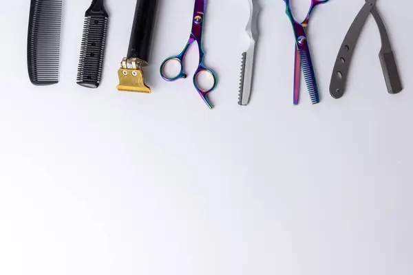 stock image A clean, white background highlights a neatly arranged lineup of barber tools including scissors, clippers, and razors. Ideal for depicting professional grooming equipment