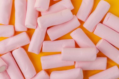 Yukarıdan bakıldığında, bu yatay görüntü çerçevenin üst kısmını kaplayan marşmelovların dağınık bir düzenini gösteriyor. Parlak sarı arkaplan görsel kontrastı ve çekiciliği arttırır.