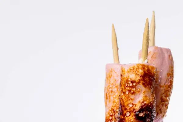 stock image Close-up of skewered marshmallows, perfectly toasted and detailed, on a vertical photo with a white background. The skewers are neatly aligned on the right side of the frame