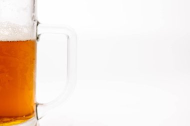 Kavrulmuş bir bira bardağının gövdesinin ve sapının geniş yatay görüntüsü, özellikle sol tarafa yerleştirilmiş. Temiz beyaz arkaplan kupanın ayrıntılarını ve dokusunu vurgular