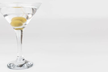 Çerçevenin soluna yerleştirilmiş iki zeytinli martini bardağının yakın çekim yatay görüntüsü. Beyaz arka plan, odak noktasının cam ve içindekiler üzerinde kalmasını sağlar.
