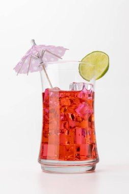 Limon dilimi ve dekoratif kağıt şemsiyeyle süslenmiş bol buzlu pembe limonata içeceği içeren dikey görüntü. Beyaz arka plan içkinin cazibesini arttırır.