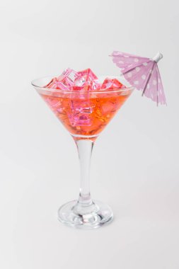 Limon dilimi ve küçük bir şemsiye ile süslenmiş, buzla dolu pembe bir limonata içeceğinin yukarıdan aşağı dikey görüntüsü.