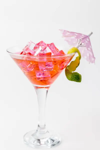 stock image Vertical image showing a pink lemonade cocktail with ice, a lemon slice, and a paper umbrella, placed centrally against a white background for a fresh, vibrant look