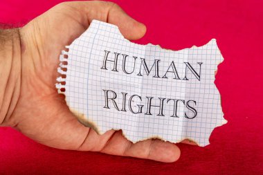 Kısmen yanmış bir kağıdı tutan eli gösteren yakın plan bir fotoğraf. 