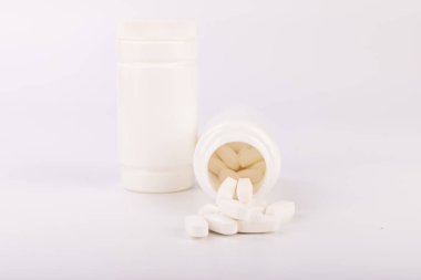 Arious ilaç şişeleri, içinde görünür haplar da var. Arka plan sade beyaz, sağlık ve ilaç konuları için mükemmel.