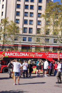 Barselona, İspanya - 15 Eylül 2024: Plaza Cataluna 'nın göbeğinde turistler, Barcelona turnesi için kırmızı çift katlı otobüslere binmek üzere sırada bekliyorlar.