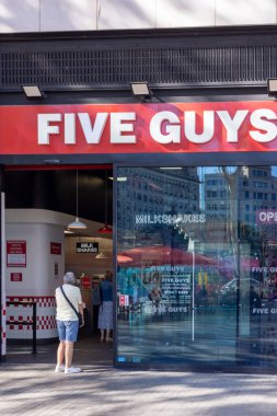 Barselona, İspanya - 15 Eylül 2024: Bir grup insan Plaza Cataluna 'da canlı bir şehir merkezindeki ünlü hamburger zincirinin altını çizerek bir Beş Adam' a girerken yakalandı