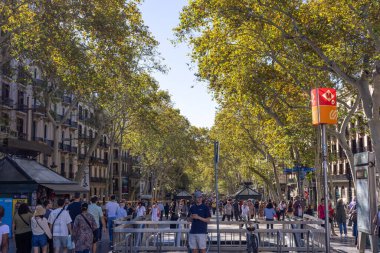 Barselona, İspanya - 15 Eylül 2024: La Rambla, insanlar dükkanlar, sokak sanatçıları ve hareketli kalabalıklarla çevrili yoğun yolunda yürürken hareketlilik içinde.