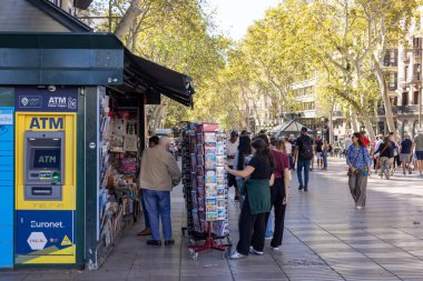 Barselona, İspanya - 15 Eylül 2024: La Rambla 'da kalabalık bir gazete büfesi ve ATM, insanların Barselona sembolik caddesinde gezinirken alışveriş yapmak için durduğu