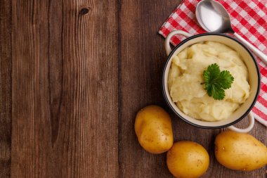 Patatesli bir kasede patates püresi ve ahşap bir masada kırmızı bir peçete.