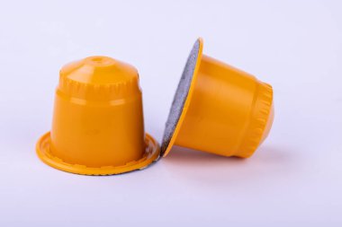 Beyaz bir yüzeye saçılmış sarı kahve kapsülleri. Parlak tasarım, markalaşma ve pazarlama için ideal minimum, modern bir ortamda göze çarpıyor.