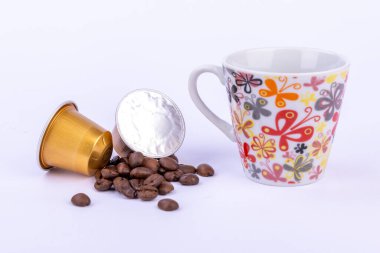 A bright setup showcasing golden coffee capsules, scattered coffee beans, and a cup, perfect for coffee enthusiasts clipart