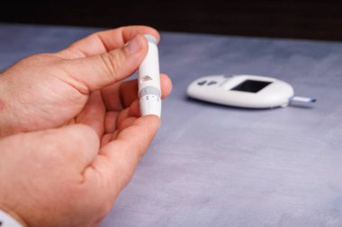 Close-up view of a person conducting a blood glucose test on a concrete table, emphasizing the device and the meticulous procedure clipart