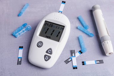 Detailed shot of a glucometer with test strips and lancets on a concrete table, highlighting the tools used for glucose testing and health monitoring clipart