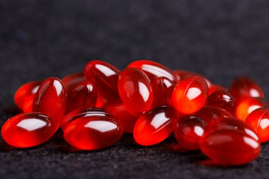 Siyah arkaplanda kırmızı şeffaf hapların detaylı bir görüntüsü, parlak tasarımları ve canlı renkleri, sağlıkla ilgili konular için mükemmel.
