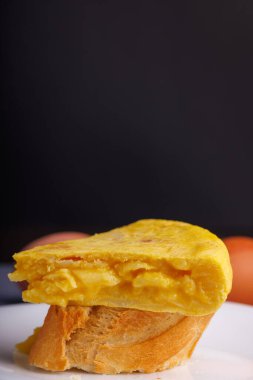 İspanyol omlet şiş yakın plan ekmek, arka planda yumurtalar, mavi beton masa, geleneksel İspanyol mutfağını temsil ediyor