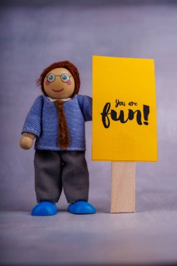 Tahta bir figür motivasyon tabiriyle sarı bir pankart tutar, minimalist ve temiz bir fotoğraf düzeninde pozitifliği ve umudu teşvik eder.