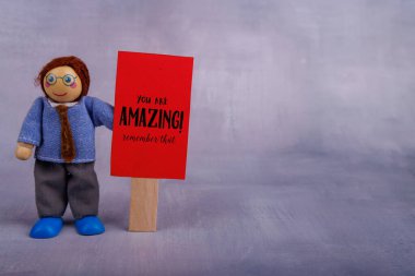 Gülümseyen bir oyuncak adam kırmızı motivasyon bayrağını kavrıyor, pozitif enerji yayıyor ve umut verici bir zihniyet benimsemeleri için izleyicilere ilham veriyor.