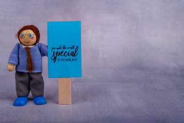 Bu ahşap oyuncak mavi bir bayrak taşıyor, olumlu alıntılarla, neşeli ve neşeli bir ortamda neşe ve cesaretlendirmeyle.