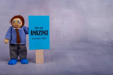 Çekici bir tahta oyuncakçı, neşeli bir sahnede motivasyon ve cesaret verici bir mesajla parlak mavi bir tabela sergiliyor.