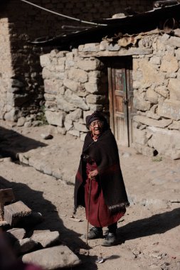 Peru - Tupe, 23 Ekim 2022: Geleneksel kıyafetler giymiş yaşlı bir kadın Peru dağlarındaki Tupe 'nin pitoresk sokaklarında yürüyor