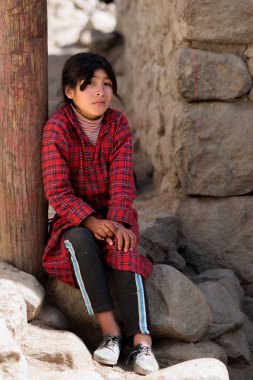 Peru - Tupe, 23 Ekim 2022: Geleneksel giysiler giymiş genç bir kadın Peru dağlarındaki Tupe caddelerinde dinleniyor.