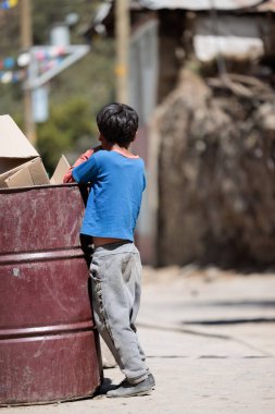 Peru - Tupe, 23 Ekim 2022: Genç bir adam Tupe dağlarında bir çöp kutusunu karıştırıyor, hayatın acı gerçeklerini vurguluyor.