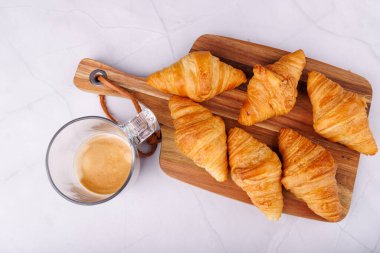 Kruvasan ve hafif mermer bir yüzey üzerinde sıcak bir fincan kahve, nefis bir kahvaltı deneyimi için mükemmel.