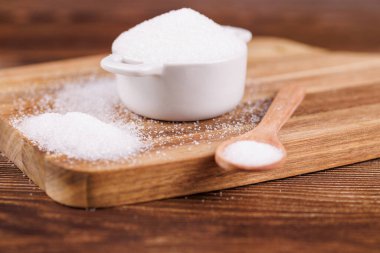 A ceramic bowl filled with sugar and a wooden spoon on a wooden table, showcasing a rustic and natural kitchen setting, perfect for food-related content clipart