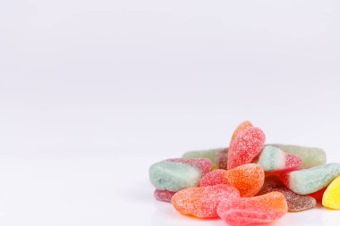 Beyaz bir arkaplan üzerine yığılmış farklı tatlarda ve parlak renklerde çeşitli jelibonlar, canlı çekiciliklerini ve tatlılıklarını vurguluyor.